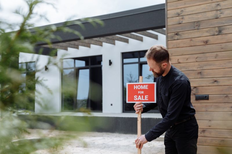 man placing a home for sale sign outside
